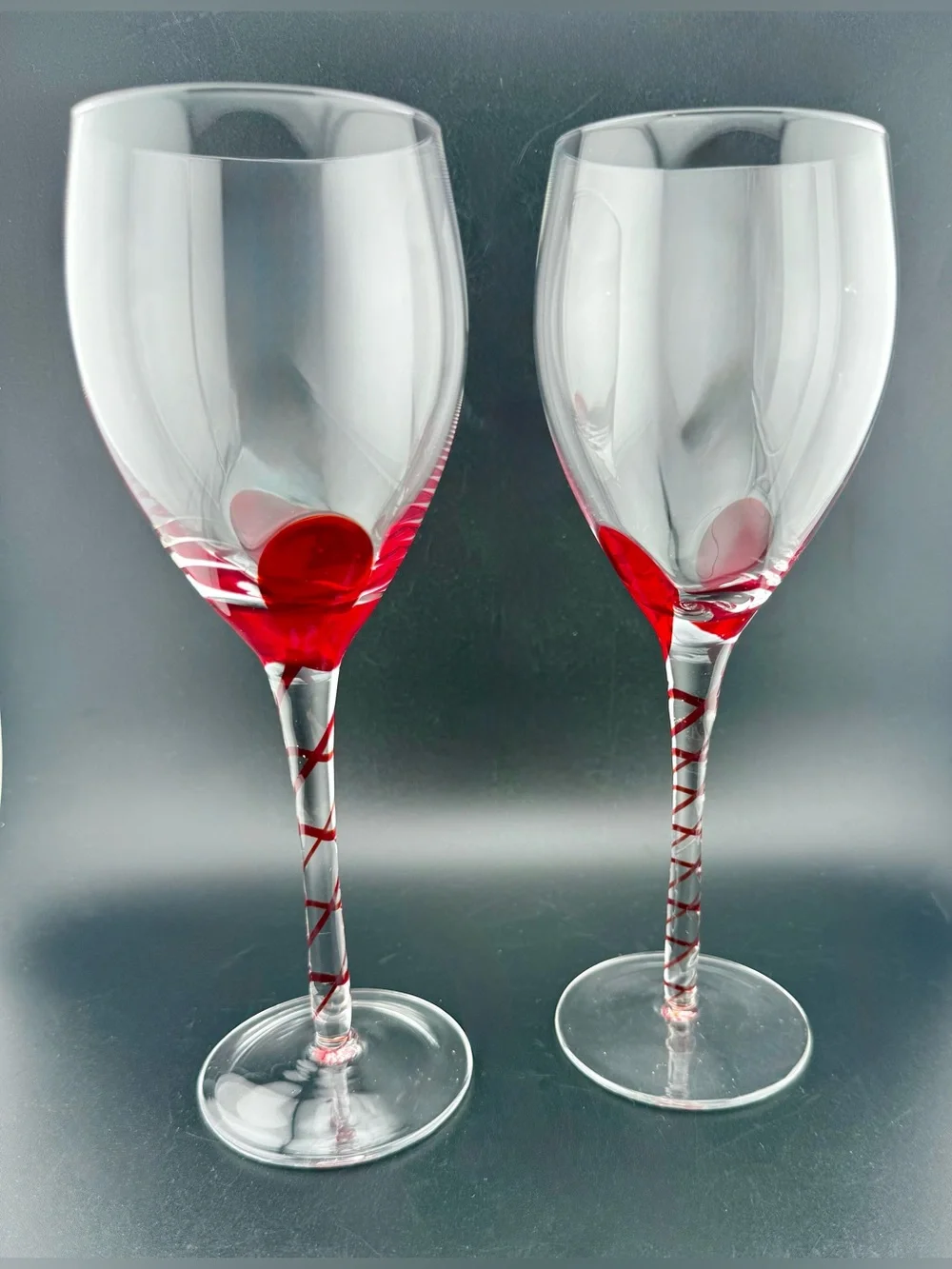 2 Pier 1, red ribbon swirl stem wine glasses, w/ a red swirl design on the stem.